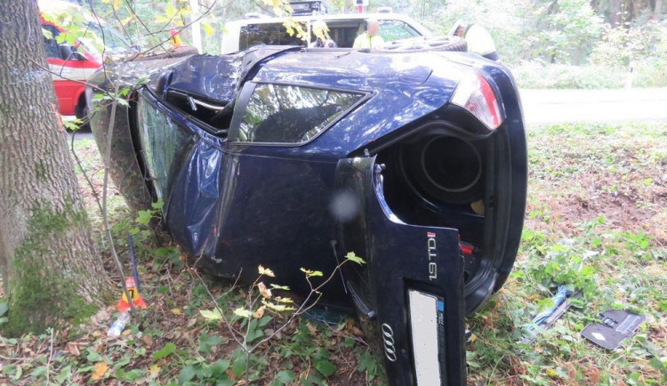 Mladý řidič podcenil mokrou vozovku, jeho auto se převrátilo na bok a narazilo do stromu