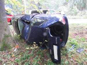 Mladý řidič podcenil mokrou vozovku, jeho auto se převrátilo na bok a narazilo do stromu