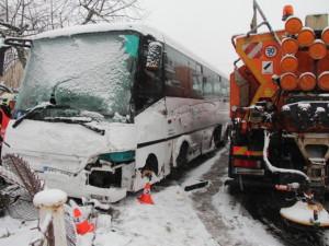 Autobus se srazil se sypačem a skončil v plotu rodinného domu, řidič byl převezen do nemocnice