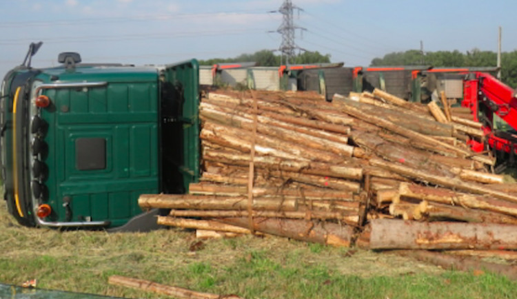 Řidič kamionu se dřevem nevybral zatáčku a skončil s vysypaným nákladem v poli