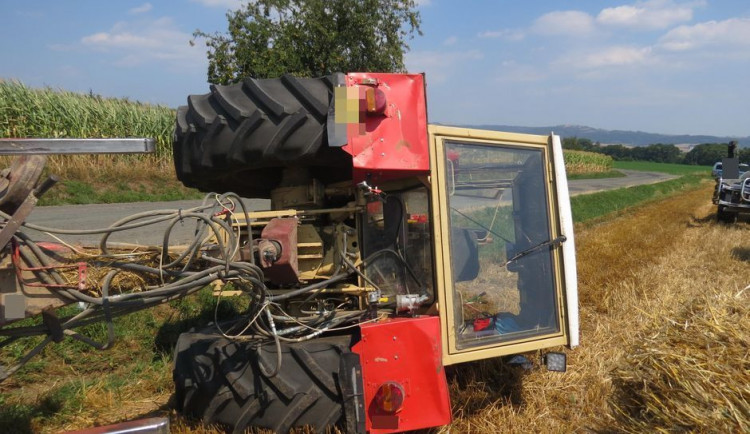 Traktorista jel příliš blízko krajnice, se strojem i s převáženou slámou skončil převrácený mimo silnici