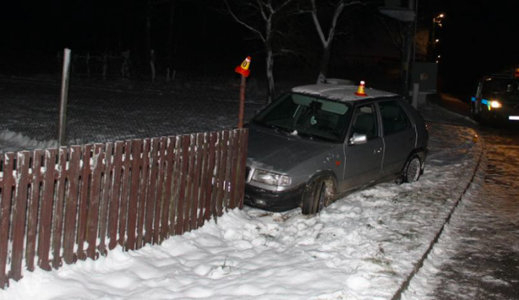 Opilý řidič nezvládl na letních gumách zatáčku a skončil v oplocení domu