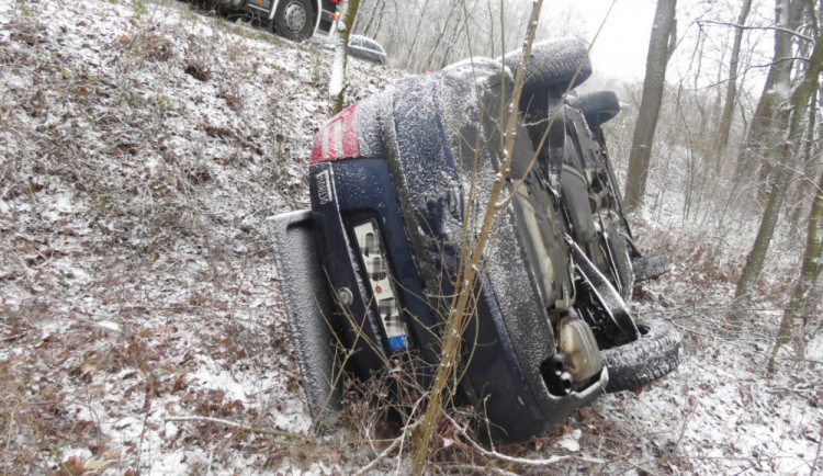 Žena podcenila jízdu po ujetém sněhu a dostala smyk. Škodovka skončila na střeše v blízkém lese