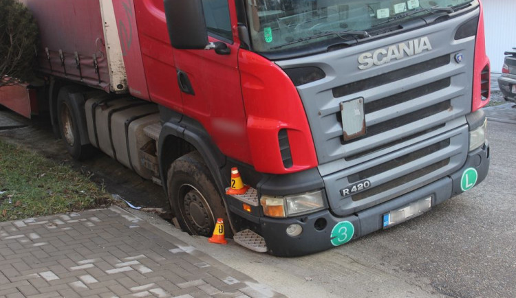 Řidič kamionu při couvání najel na kanál, do kterého se propadl i s kusem silnice
