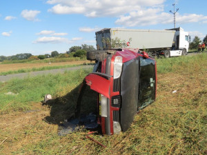 Řidič náklaďáku přehlédl pomalu jedoucí osobák a narazil do něj. Jeho řidička skončila v převráceném voze na poli